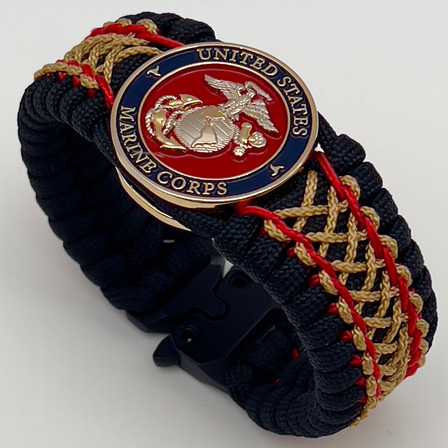 Thick and comfortable braided United States Marine Corps bracelet featuring a 24K gold and silver plated USMC officer Eagle Globe and Anchor medallion, a black Cobra style tactical buckle and woven with black 550 paracord and Imperial Red and gold micro cord.