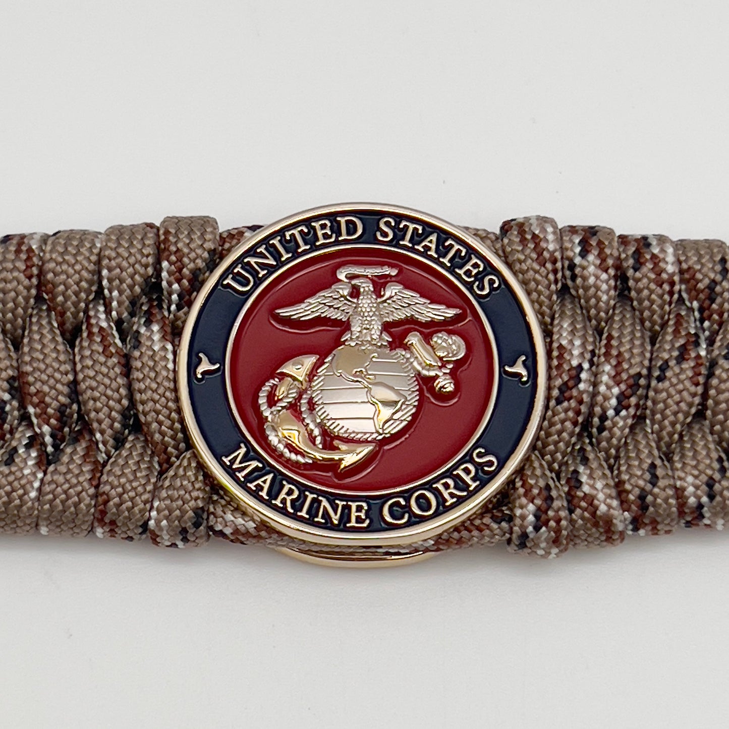 Thick and comfortable braided United States Marine Corps bracelet featuring a 24K gold and silver plated USMC officer Eagle Globe and Anchor medallion, a gold Cobra style tactical buckle and woven with Desert Camo 550 paracord.