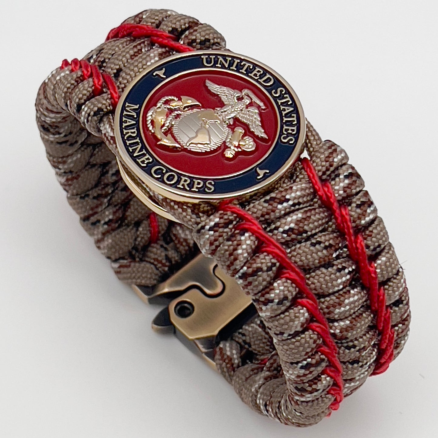 Thick and comfortable braided United States Marine Corps bracelet featuring a 24K gold and silver plated USMC officer Eagle Globe and Anchor medallion, a gold Cobra style tactical buckle and woven with Desert Camo 550 paracord and Imperial Red micro cord.