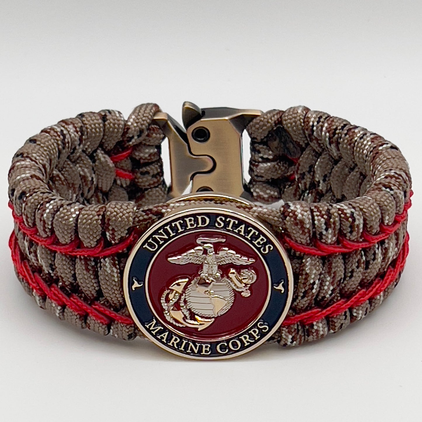 Thick and comfortable braided United States Marine Corps bracelet featuring a 24K gold and silver plated USMC officer Eagle Globe and Anchor medallion, a gold Cobra style tactical buckle and woven with Desert Camo 550 paracord and Imperial Red micro cord.