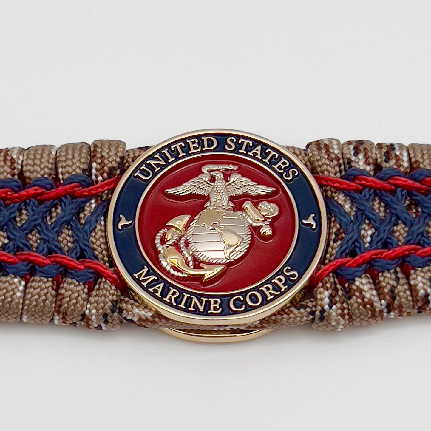 Thick and comfortable braided United States Marine Corps bracelet featuring a 24K gold and silver plated USMC officer Eagle Globe and Anchor medallion, a gold Cobra style tactical buckle and woven with Desert Camo 550 paracord and Imperial Red and Navy Blue micro cord.