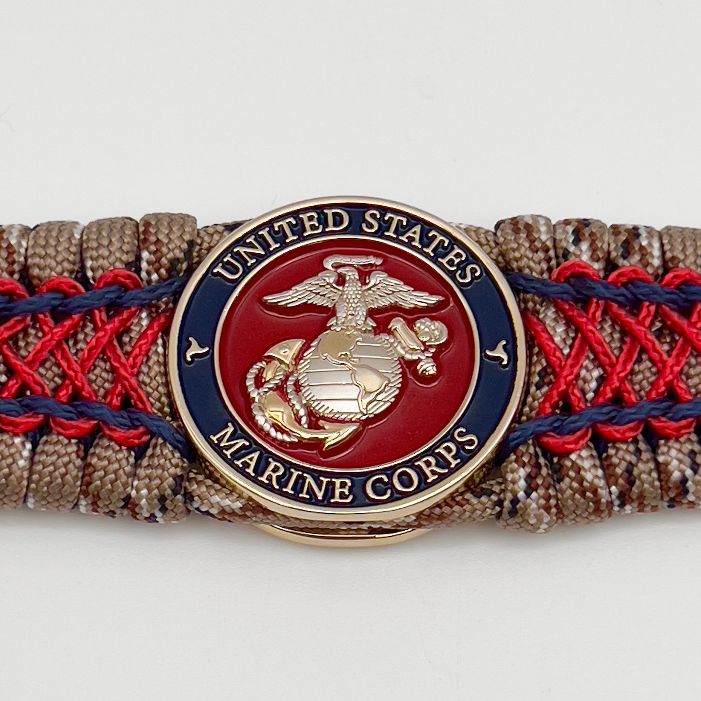 Thick and comfortable braided United States Marine Corps bracelet featuring a 24K gold and silver plated USMC officer Eagle Globe and Anchor medallion, a gold Cobra style tactical buckle and woven with Desert Camo 550 paracord and Imperial Red and Navy Blue micro cord.
