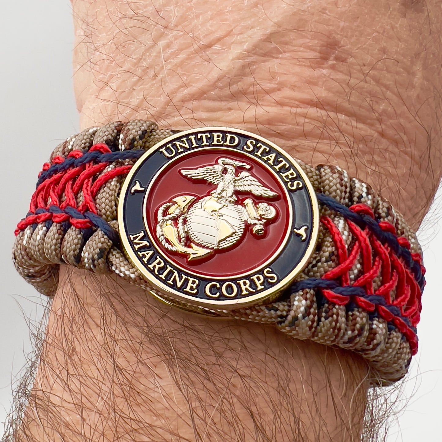 Thick and comfortable braided United States Marine Corps bracelet featuring a 24K gold and silver plated USMC officer Eagle Globe and Anchor medallion, a gold Cobra style tactical buckle and woven with Desert Camo 550 paracord and Imperial Red and Navy Blue micro cord.