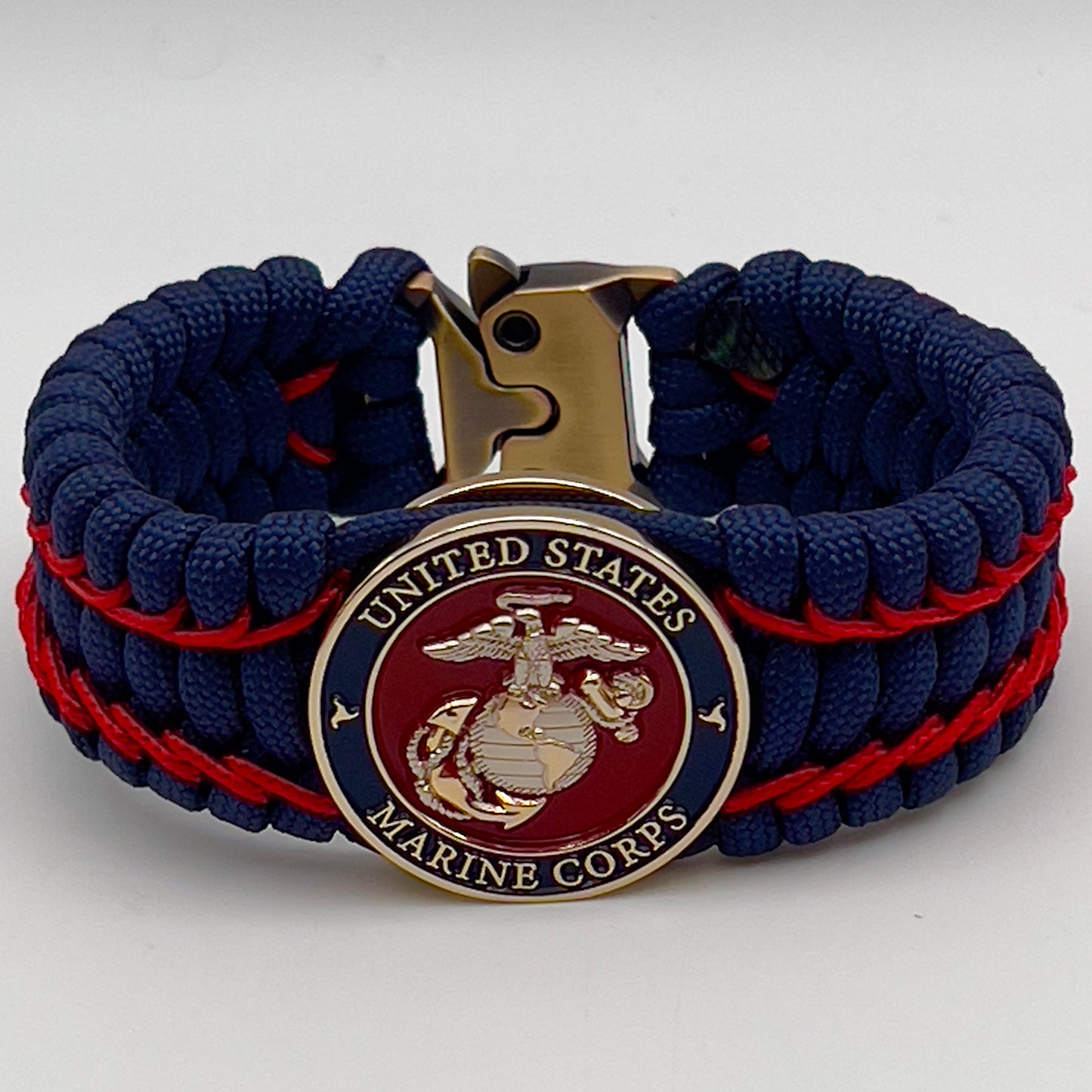 Thick and comfortable braided United States Marine Corps bracelet featuring a 24K gold and silver plated USMC officer Eagle Globe and Anchor medallion, a Cobra style tactical buckle and woven with gold 550 paracord and Imperial Red micro cord.