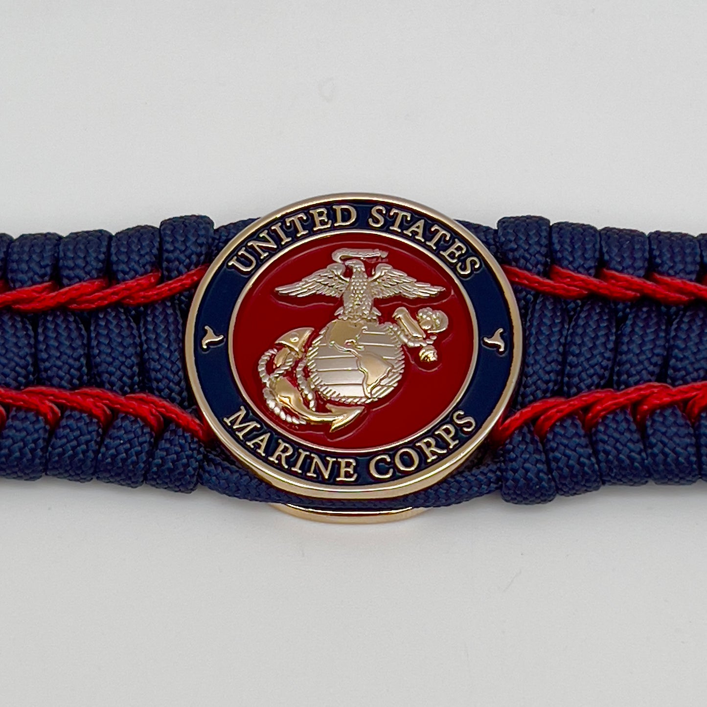 Thick and comfortable braided United States Marine Corps bracelet featuring a 24K gold and silver plated USMC officer Eagle Globe and Anchor medallion, a Cobra style tactical buckle and woven with gold 550 paracord and Imperial Red micro cord.
