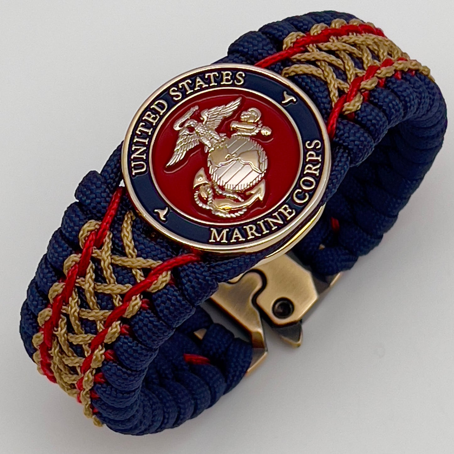Thick and comfortable braided United States Marine Corps bracelet featuring a 24K gold and silver plated USMC officer Eagle Globe and Anchor medallion, a Cobra style tactical buckle and woven with gold 550 paracord and Imperial Red and Gold micro cord.