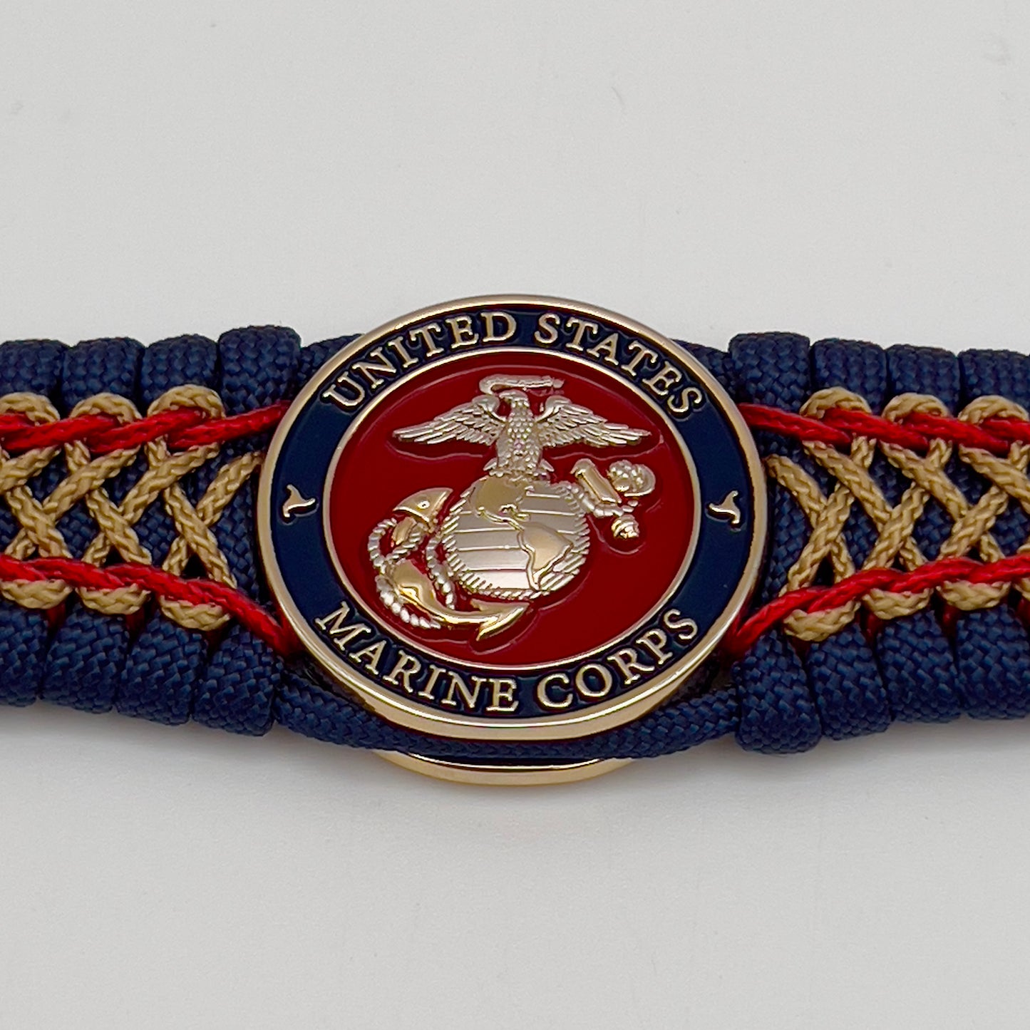 Thick and comfortable braided United States Marine Corps bracelet featuring a 24K gold and silver plated USMC officer Eagle Globe and Anchor medallion, a Cobra style tactical buckle and woven with gold 550 paracord and Imperial Red and Gold micro cord.