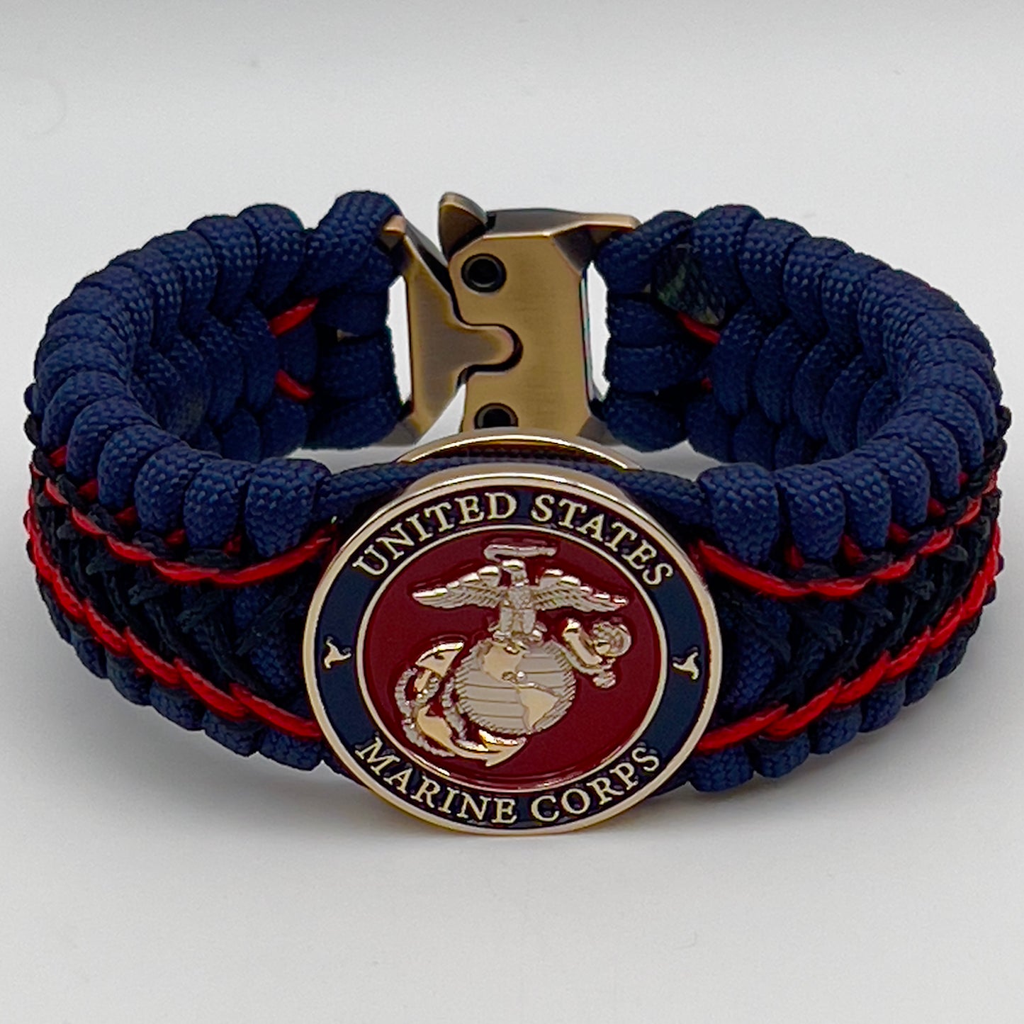 Thick and comfortable braided United States Marine Corps bracelet featuring a 24K gold and silver plated USMC officer Eagle Globe and Anchor medallion, a Cobra style tactical buckle and woven with gold 550 paracord and Imperial Red and Black micro cord.