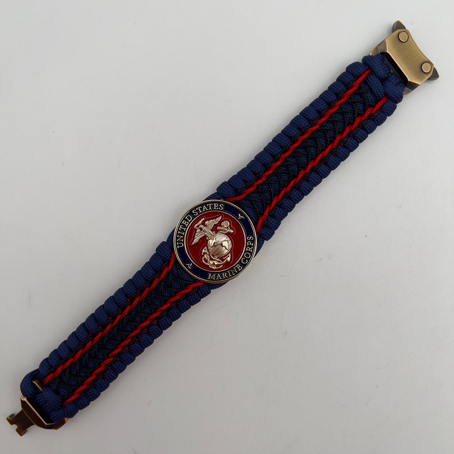 Thick and comfortable braided United States Marine Corps bracelet featuring a 24K gold and silver plated USMC officer Eagle Globe and Anchor medallion, a Cobra style tactical buckle and woven with gold 550 paracord and Imperial Red and Black micro cord.