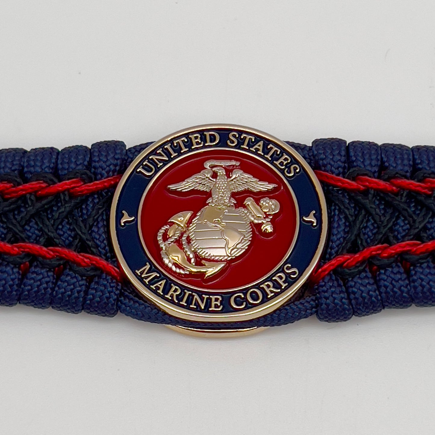 Thick and comfortable braided United States Marine Corps bracelet featuring a 24K gold and silver plated USMC officer Eagle Globe and Anchor medallion, a Cobra style tactical buckle and woven with gold 550 paracord and Imperial Red and Black micro cord.