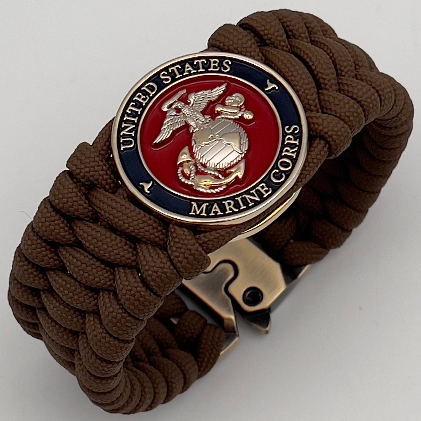 Thick and comfortable braided United States Marine Corps bracelet featuring a 24K gold and silver plated USMC officer Eagle Globe and Anchor medallion, a Cobra style tactical buckle and woven with Coyote Brown 550 paracord.