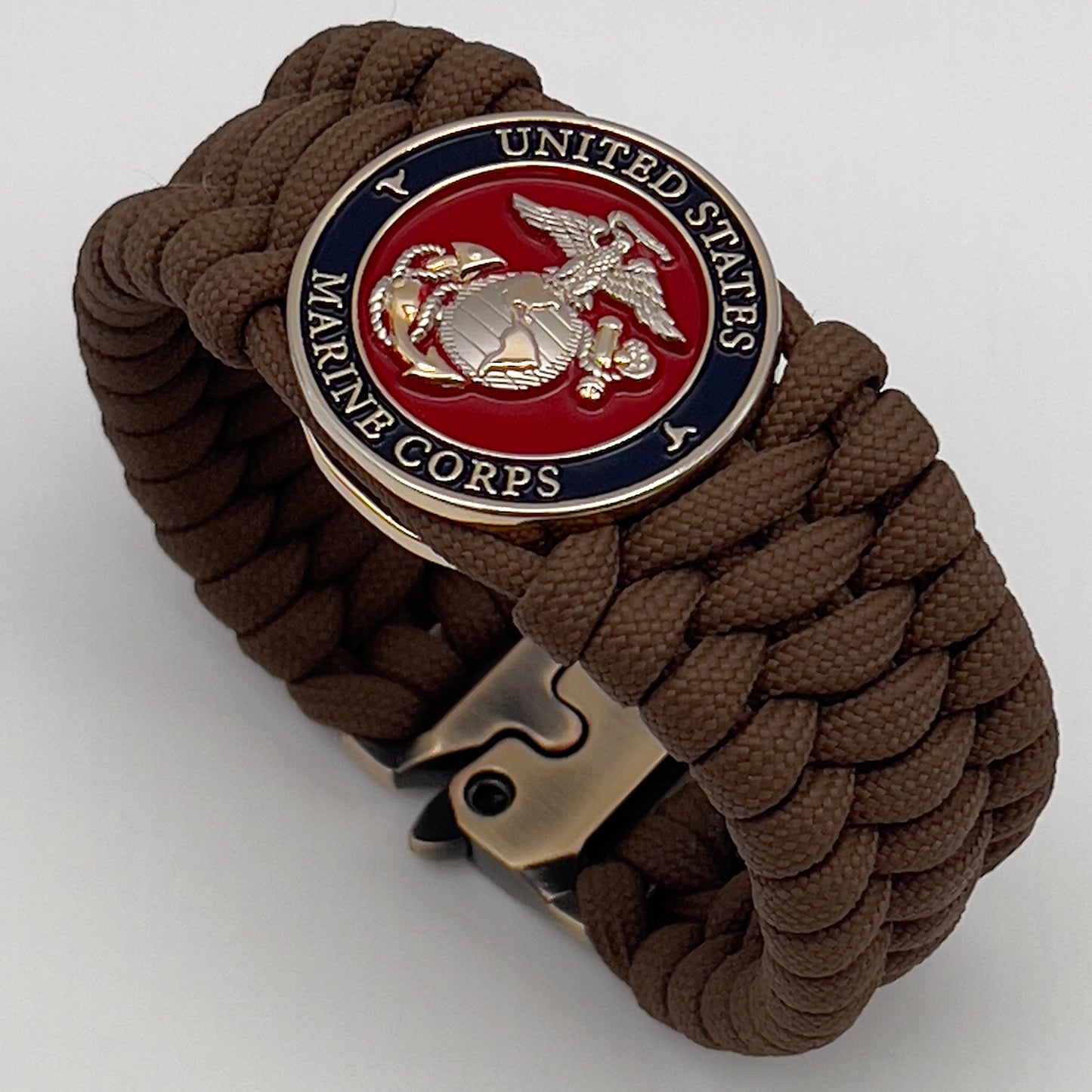 Thick and comfortable braided United States Marine Corps bracelet featuring a 24K gold and silver plated USMC officer Eagle Globe and Anchor medallion, a Cobra style tactical buckle and woven with Coyote Brown 550 paracord.