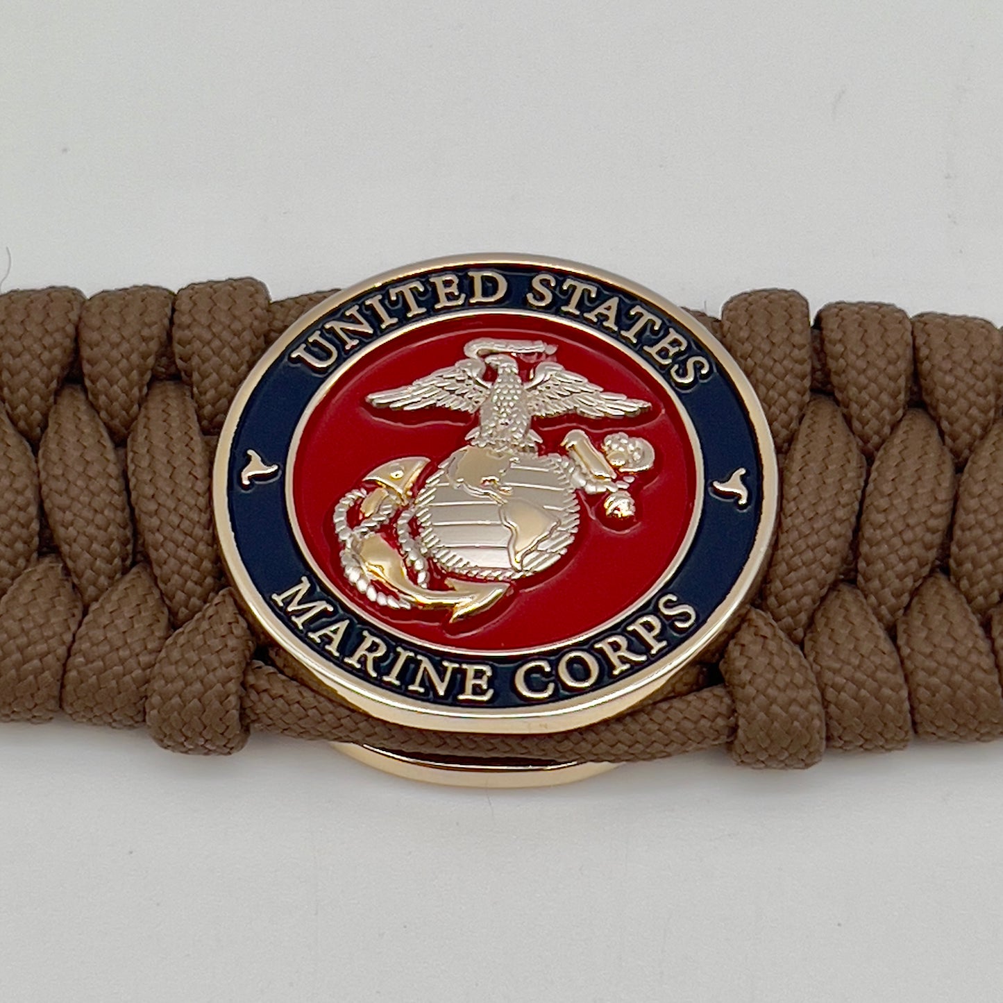 Thick and comfortable braided United States Marine Corps bracelet featuring a 24K gold and silver plated USMC officer Eagle Globe and Anchor medallion, a Cobra style tactical buckle and woven with Coyote Brown 550 paracord.