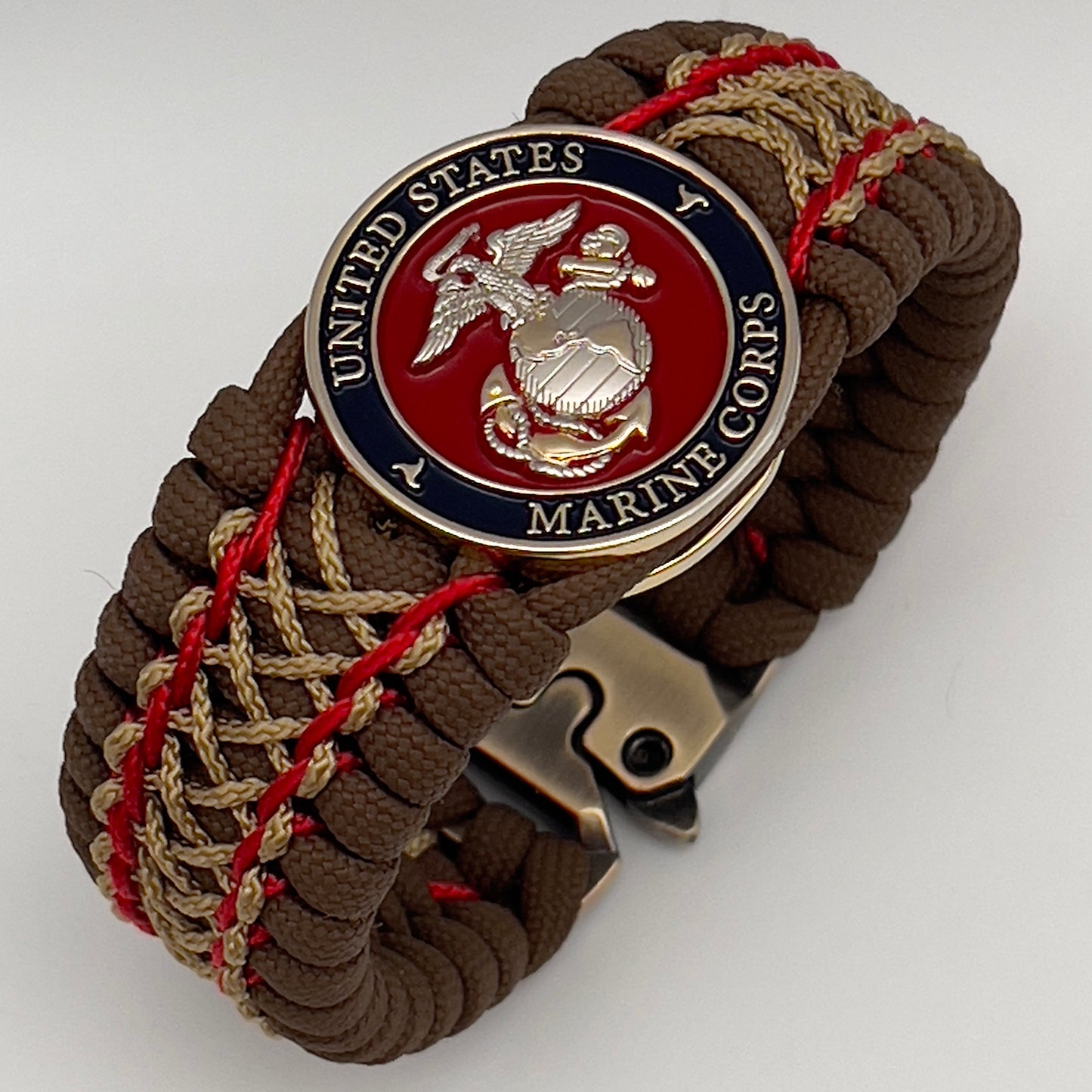 Thick and comfortable braided United States Marine Corps bracelet featuring a 24K gold and silver plated USMC officer Eagle Globe and Anchor medallion, a Cobra style tactical buckle and woven with Coyote Brown 550 paracord and Imperial Red and gold micro cord.