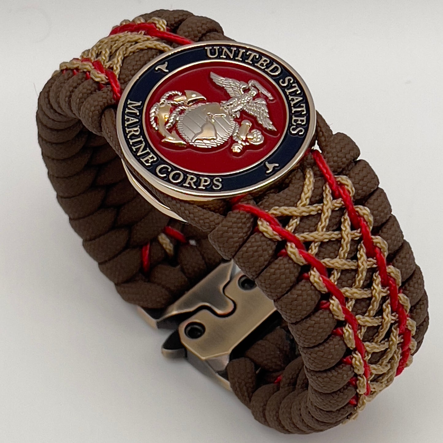 Thick and comfortable braided United States Marine Corps bracelet featuring a 24K gold and silver plated USMC officer Eagle Globe and Anchor medallion, a Cobra style tactical buckle and woven with Coyote Brown 550 paracord and Imperial Red and gold micro cord.