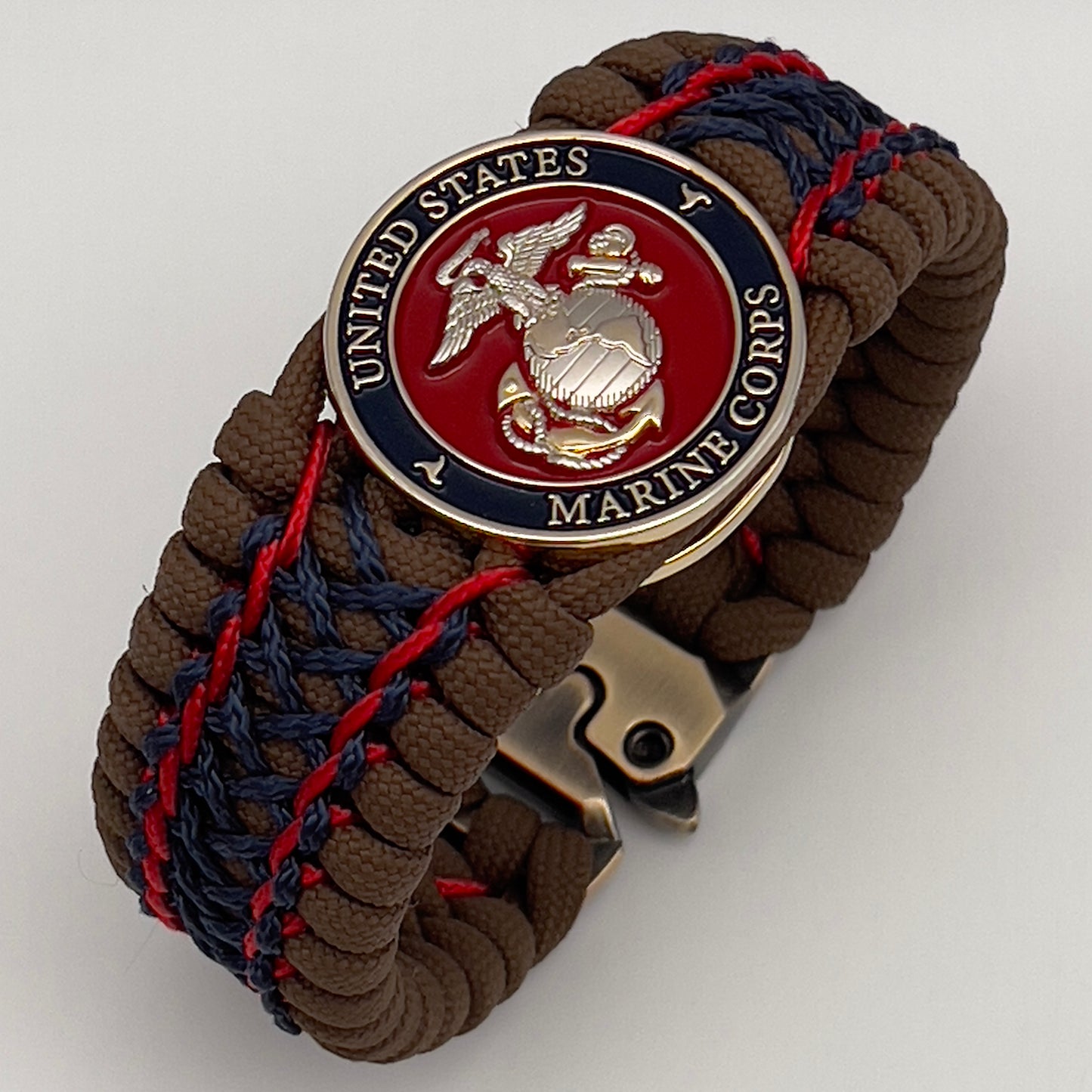 Thick and comfortable braided United States Marine Corps bracelet featuring a 24K gold and silver plated USMC officer Eagle Globe and Anchor medallion, a Cobra style tactical buckle and woven with Coyote Brown 550 paracord and Imperial Red and Navy Blue micro cord.