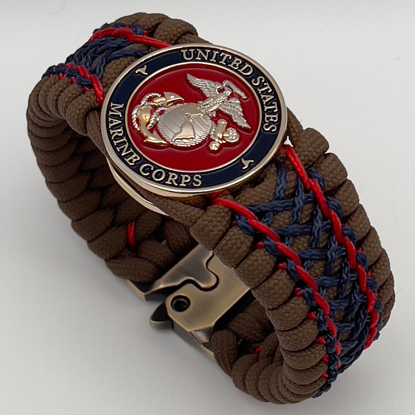 Thick and comfortable braided United States Marine Corps bracelet featuring a 24K gold and silver plated USMC officer Eagle Globe and Anchor medallion, a Cobra style tactical buckle and woven with Coyote Brown 550 paracord and Imperial Red and Navy Blue micro cord.