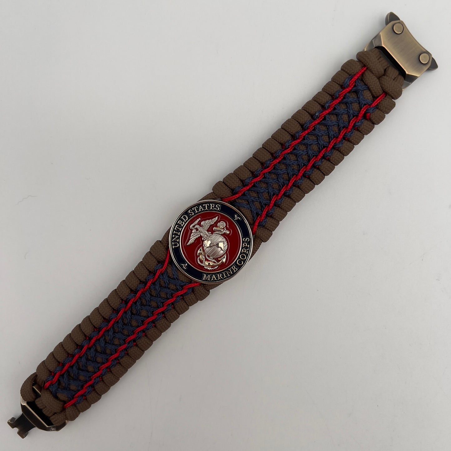 Thick and comfortable braided United States Marine Corps bracelet featuring a 24K gold and silver plated USMC officer Eagle Globe and Anchor medallion, a Cobra style tactical buckle and woven with Coyote Brown 550 paracord and Imperial Red and Navy Blue micro cord.