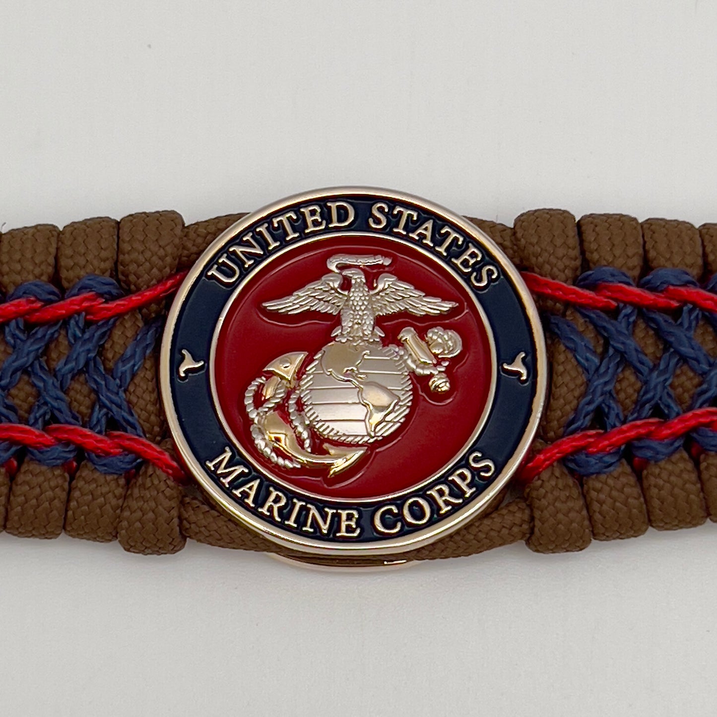 Thick and comfortable braided United States Marine Corps bracelet featuring a 24K gold and silver plated USMC officer Eagle Globe and Anchor medallion, a Cobra style tactical buckle and woven with Coyote Brown 550 paracord and Imperial Red and Navy Blue micro cord.