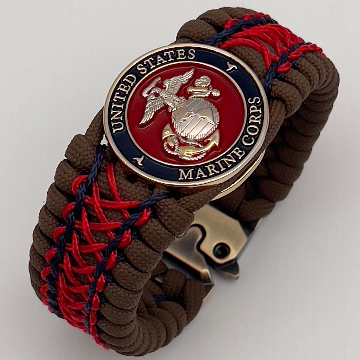 Thick and comfortable braided United States Marine Corps bracelet featuring a 24K gold and silver plated USMC officer Eagle Globe and Anchor medallion, a Cobra style tactical buckle and woven with Coyote Brown 550 paracord and Imperial Red and Navy Blue micro cord.