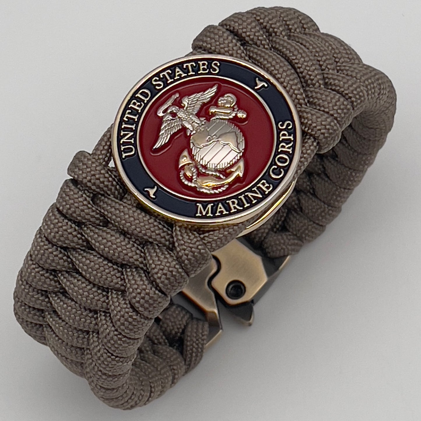 Thick and comfortable braided United States Marine Corps bracelet featuring a 24K gold and silver plated USMC officer Eagle Globe and Anchor medallion, a Cobra style tactical buckle and woven with tan 550 paracord.
