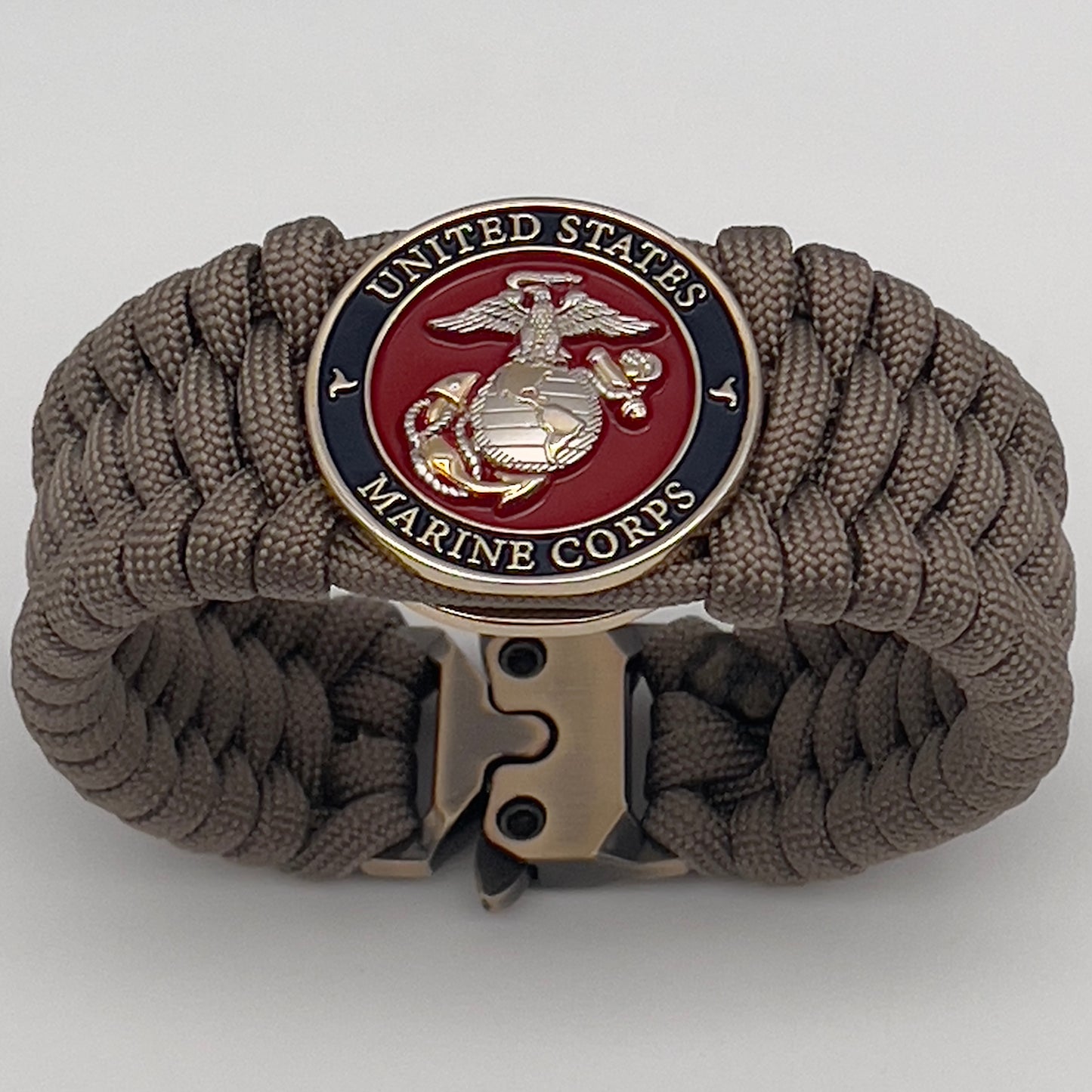 Thick and comfortable braided United States Marine Corps bracelet featuring a 24K gold and silver plated USMC officer Eagle Globe and Anchor medallion, a Cobra style tactical buckle and woven with tan 550 paracord.