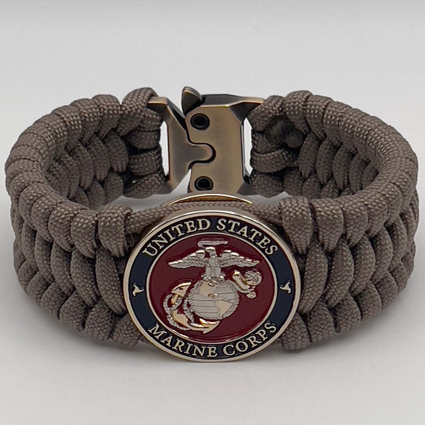 Thick and comfortable braided United States Marine Corps bracelet featuring a 24K gold and silver plated USMC officer Eagle Globe and Anchor medallion, a Cobra style tactical buckle and woven with tan 550 paracord.