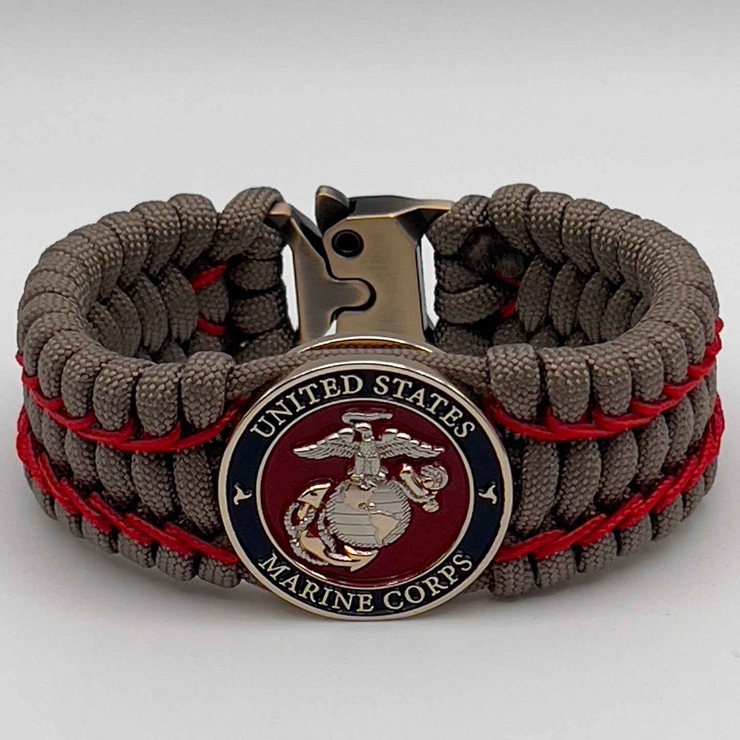 Thick, semi-rigid and comfortable braided United States Marine Corps bracelet featuring a 24K gold and silver plated USMC officer Eagle Globe and Anchor medallion, a gold Cobra style tactical buckle and woven with tan 550 paracord and Imperial Red micro cord.