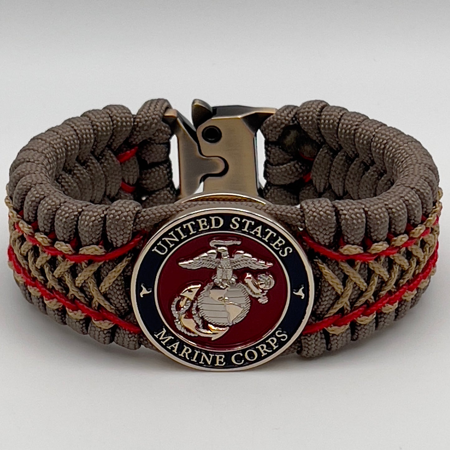 Thick, semi-rigid and comfortable braided United States Marine Corps bracelet featuring a 24K gold and silver plated USMC officer Eagle Globe and Anchor medallion, a gold Cobra style tactical buckle and woven with tan 550 paracord and Imperial Red and gold micro cord.