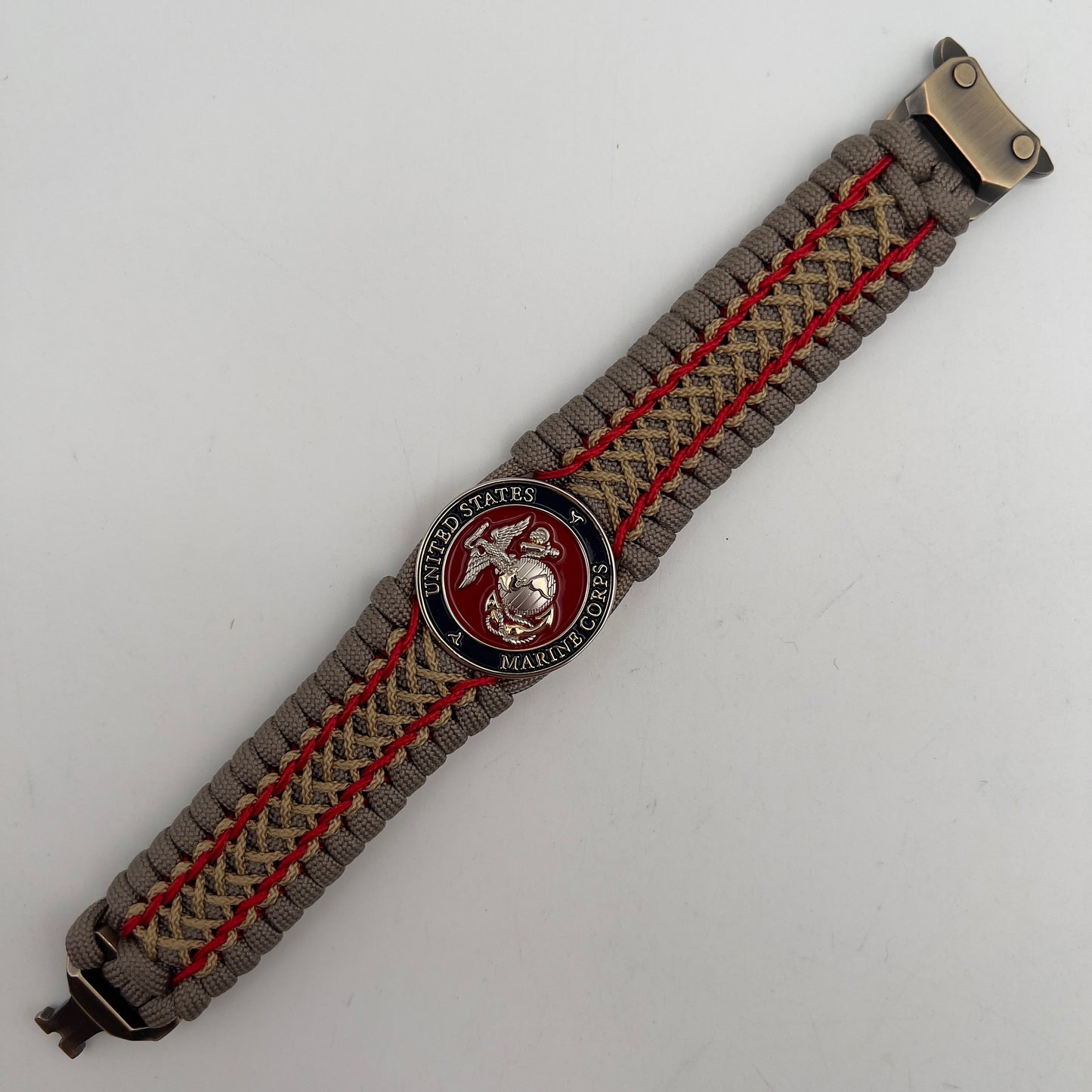 Thick, semi-rigid and comfortable braided United States Marine Corps bracelet featuring a 24K gold and silver plated USMC officer Eagle Globe and Anchor medallion, a gold Cobra style tactical buckle and woven with tan 550 paracord and Imperial Red and gold micro cord.