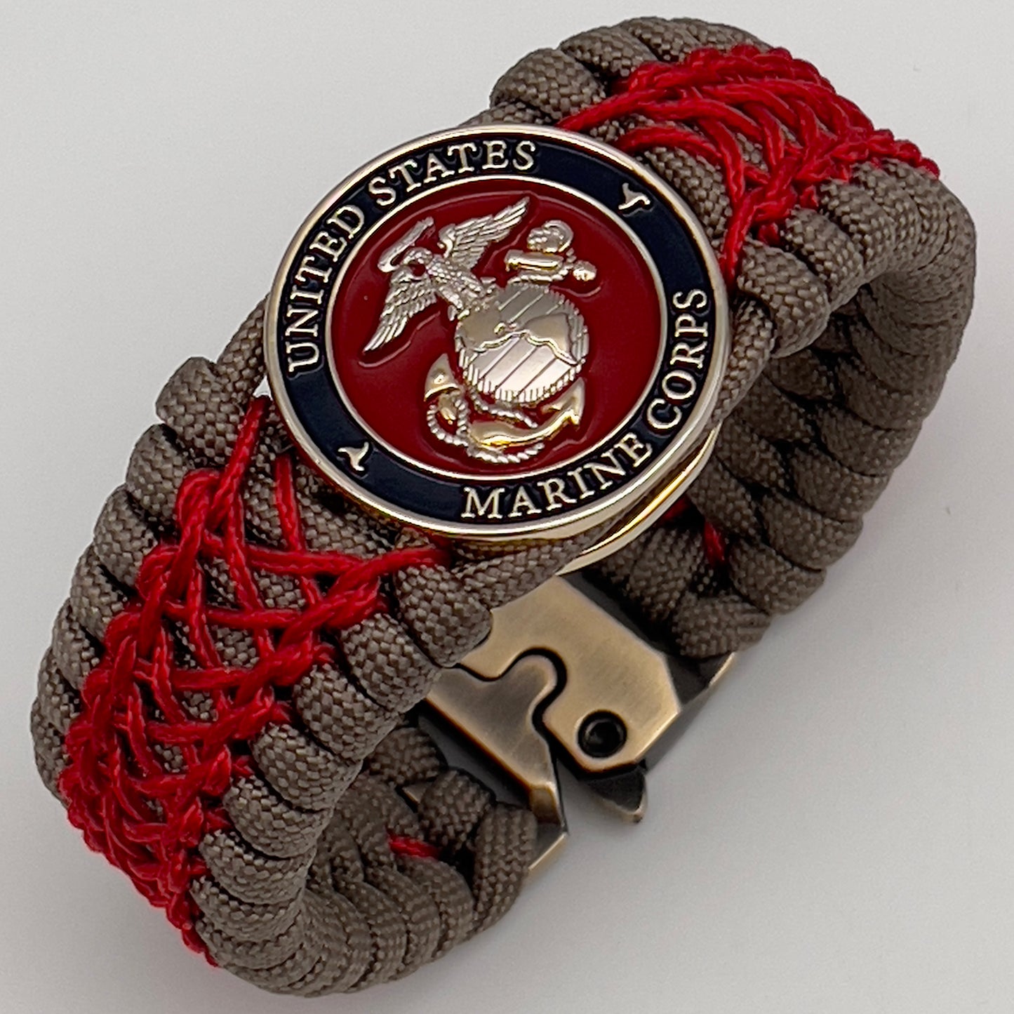 Thick, semi-rigid and comfortable braided United States Marine Corps bracelet featuring a 24K gold and silver plated USMC officer Eagle Globe and Anchor medallion, a gold Cobra style tactical buckle and woven with tan 550 paracord and Imperial red micro cord.