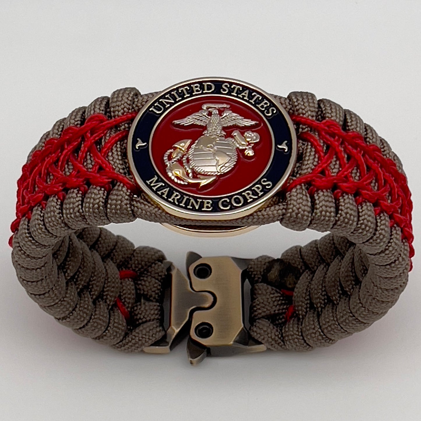 Thick, semi-rigid and comfortable braided United States Marine Corps bracelet featuring a 24K gold and silver plated USMC officer Eagle Globe and Anchor medallion, a gold Cobra style tactical buckle and woven with tan 550 paracord and Imperial red micro cord.