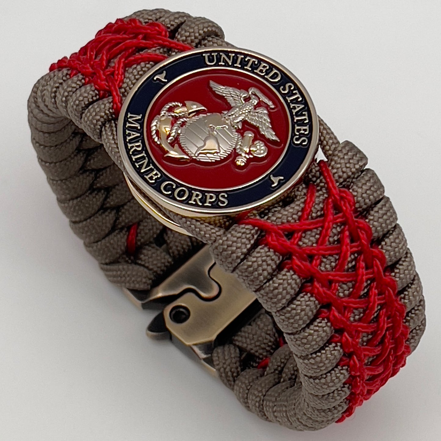 Thick, semi-rigid and comfortable braided United States Marine Corps bracelet featuring a 24K gold and silver plated USMC officer Eagle Globe and Anchor medallion, a gold Cobra style tactical buckle and woven with tan 550 paracord and Imperial red micro cord.