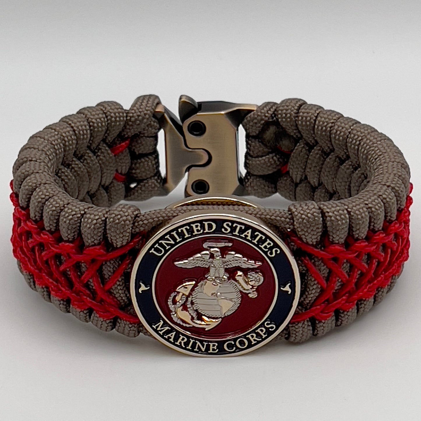 Thick, semi-rigid and comfortable braided United States Marine Corps bracelet featuring a 24K gold and silver plated USMC officer Eagle Globe and Anchor medallion, a gold Cobra style tactical buckle and woven with tan 550 paracord and Imperial red micro cord.