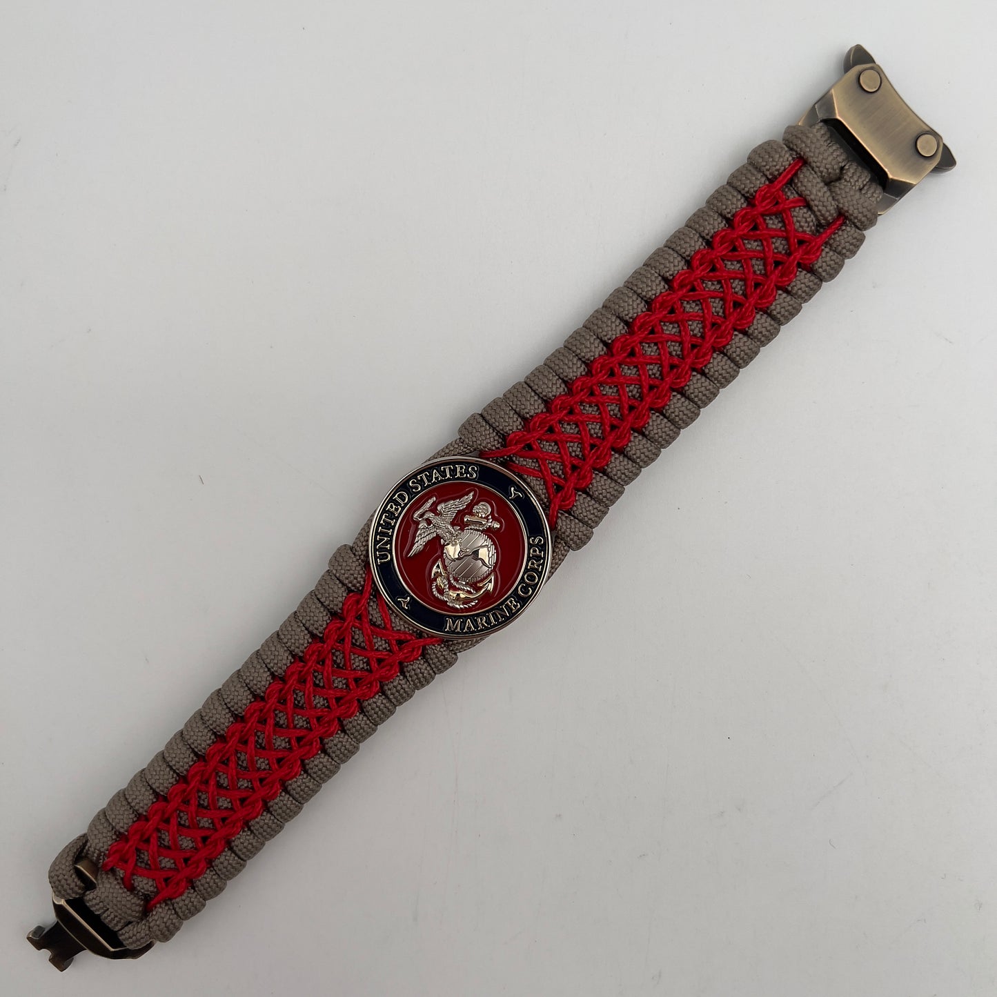 Thick, semi-rigid and comfortable braided United States Marine Corps bracelet featuring a 24K gold and silver plated USMC officer Eagle Globe and Anchor medallion, a gold Cobra style tactical buckle and woven with tan 550 paracord and Imperial red micro cord.