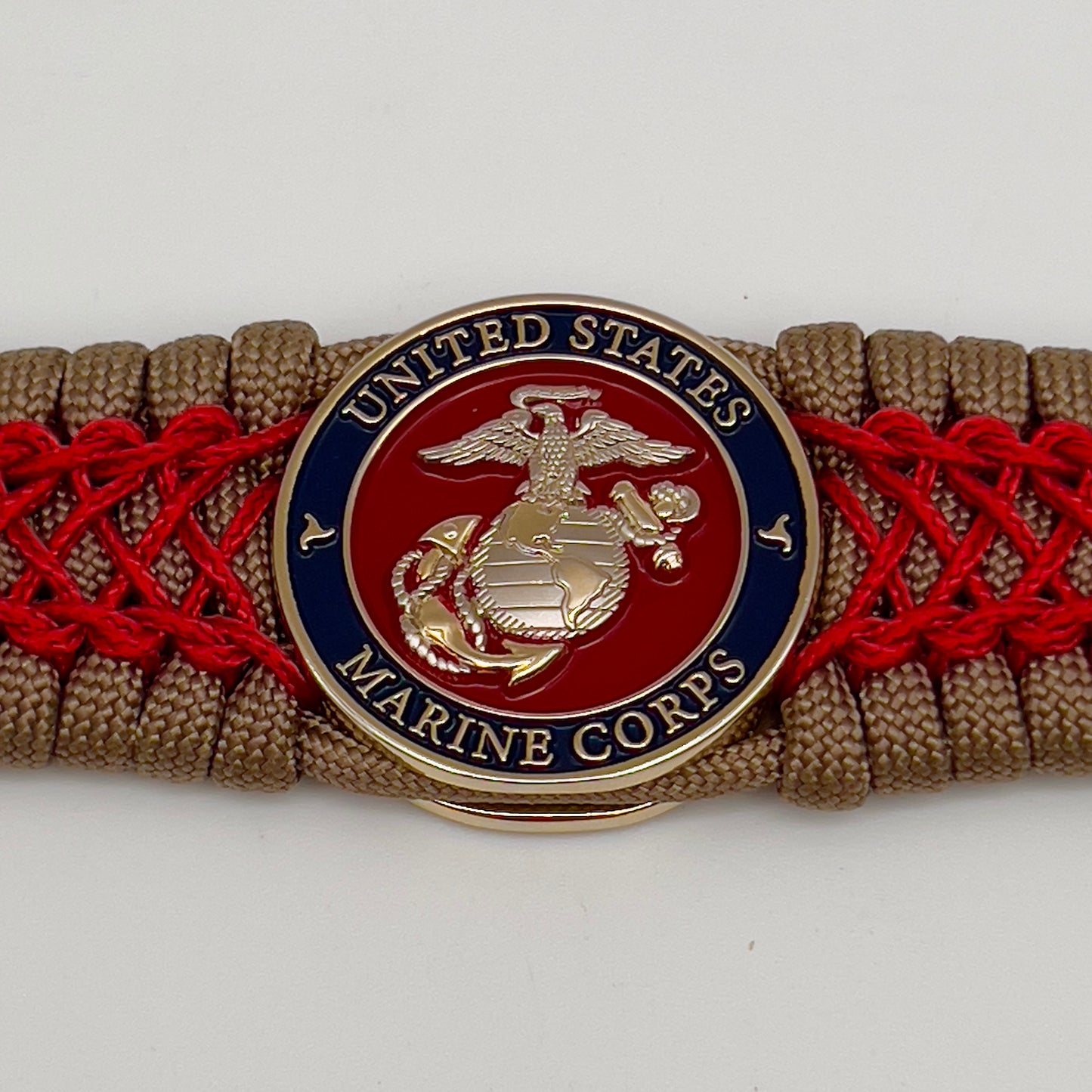 Thick, semi-rigid and comfortable braided United States Marine Corps bracelet featuring a 24K gold and silver plated USMC officer Eagle Globe and Anchor medallion, a gold Cobra style tactical buckle and woven with tan 550 paracord and Imperial red micro cord.