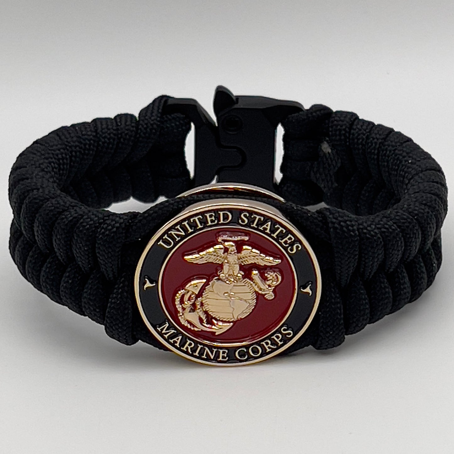 Thick, semi-rigid and comfortable braided United States Marine Corps bracelet featuring a 24K gold plated USMC officer Eagle Globe and Anchor medallion, a black Cobra style tactical buckle and woven with black 550 paracord.