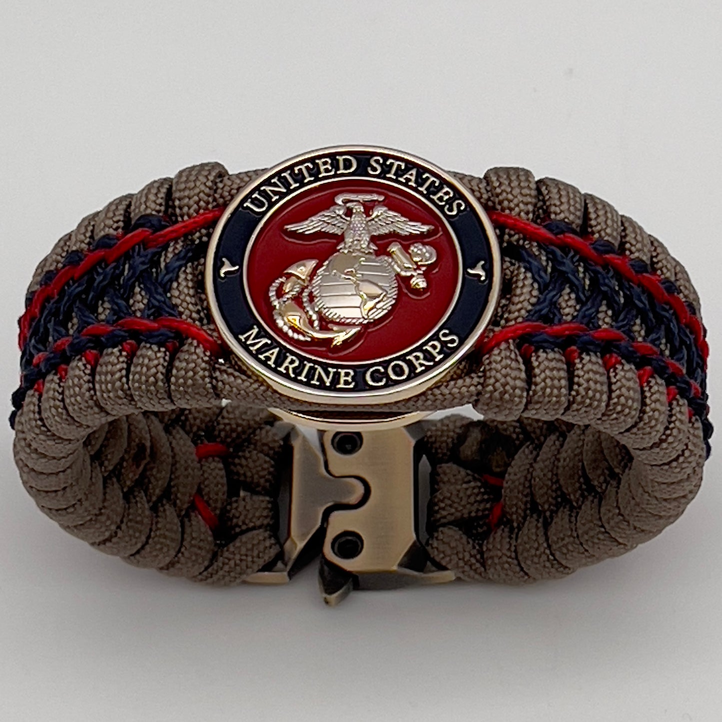 Thick, rigid and comfortable braided United States Marine Corps bracelet featuring a 24K gold and silver plated USMC officer Eagle Globe and Anchor medallion, a gold Cobra style tactical buckle and woven with tan 550 paracord and Imperial Red and Navy Blue micro cord.
