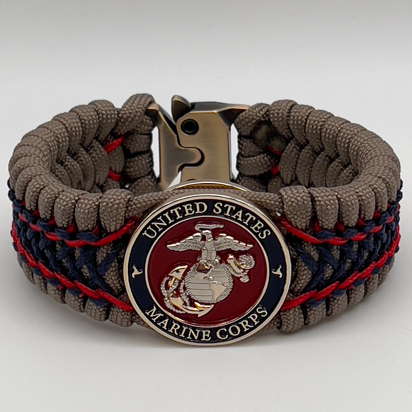 Thick, rigid and comfortable braided United States Marine Corps bracelet featuring a 24K gold and silver plated USMC officer Eagle Globe and Anchor medallion, a gold Cobra style tactical buckle and woven with tan 550 paracord and Imperial Red and Navy Blue micro cord.