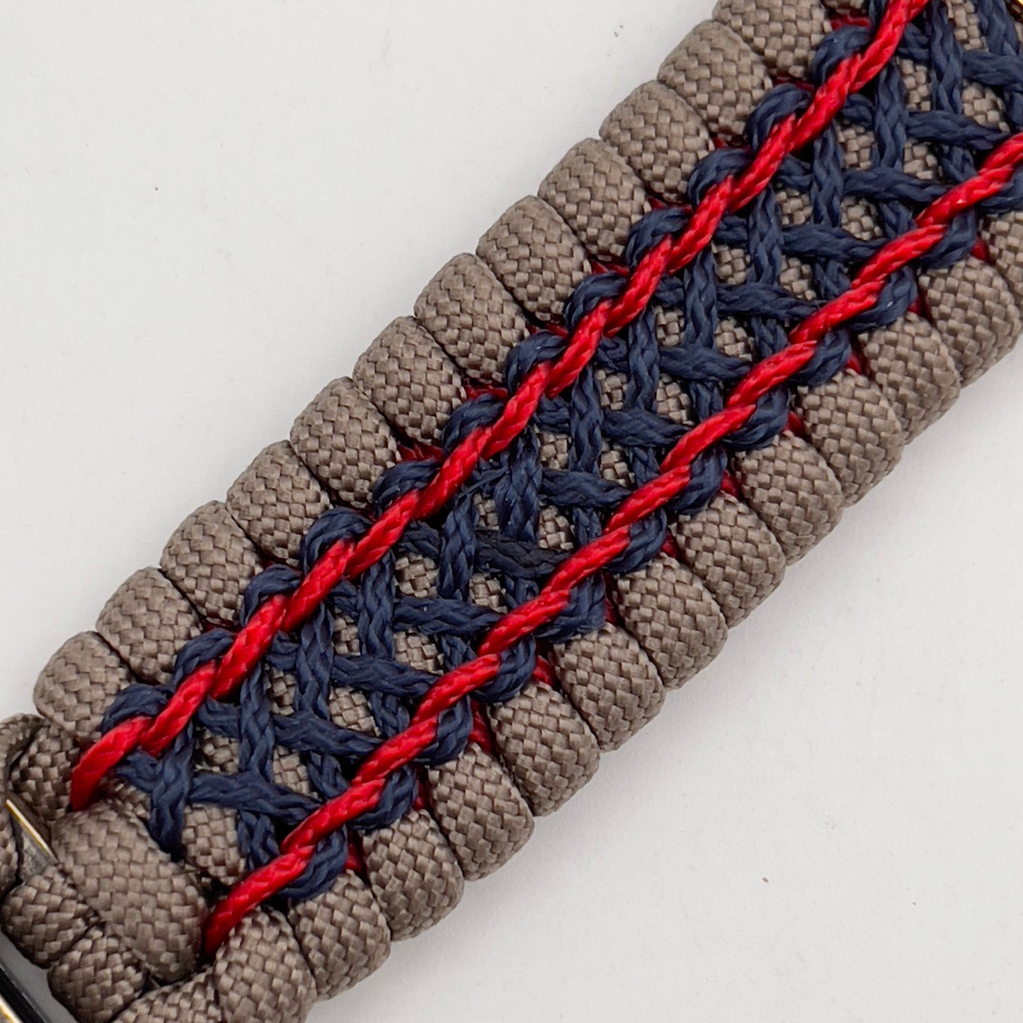 Thick, rigid and comfortable braided United States Marine Corps bracelet featuring a 24K gold and silver plated USMC officer Eagle Globe and Anchor medallion, a gold Cobra style tactical buckle and woven with tan 550 paracord and Imperial Red and Navy Blue micro cord.