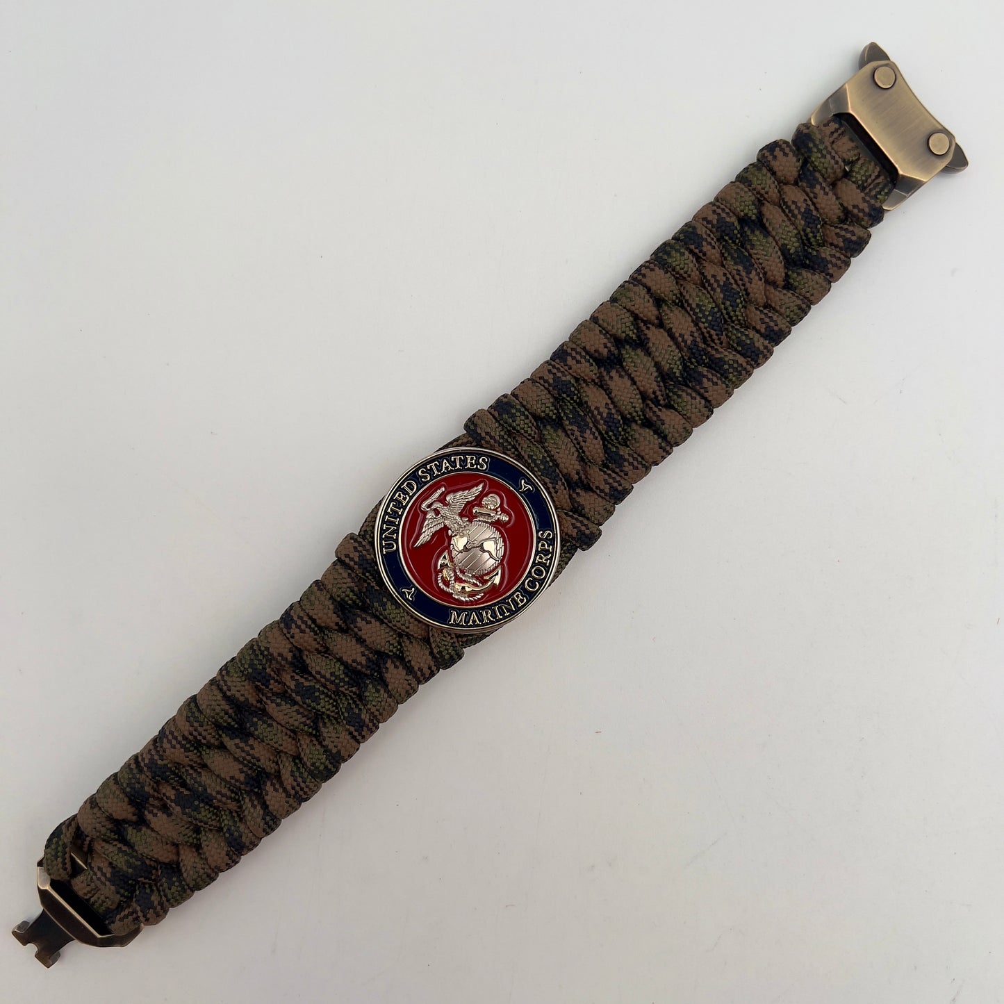 Thick, rigid and comfortable braided United States Marine Corps bracelet featuring a 24K gold and silver plated USMC officer Eagle Globe and Anchor medallion, a gold Cobra style tactical buckle and woven with Woodland Camo 550 paracord.
