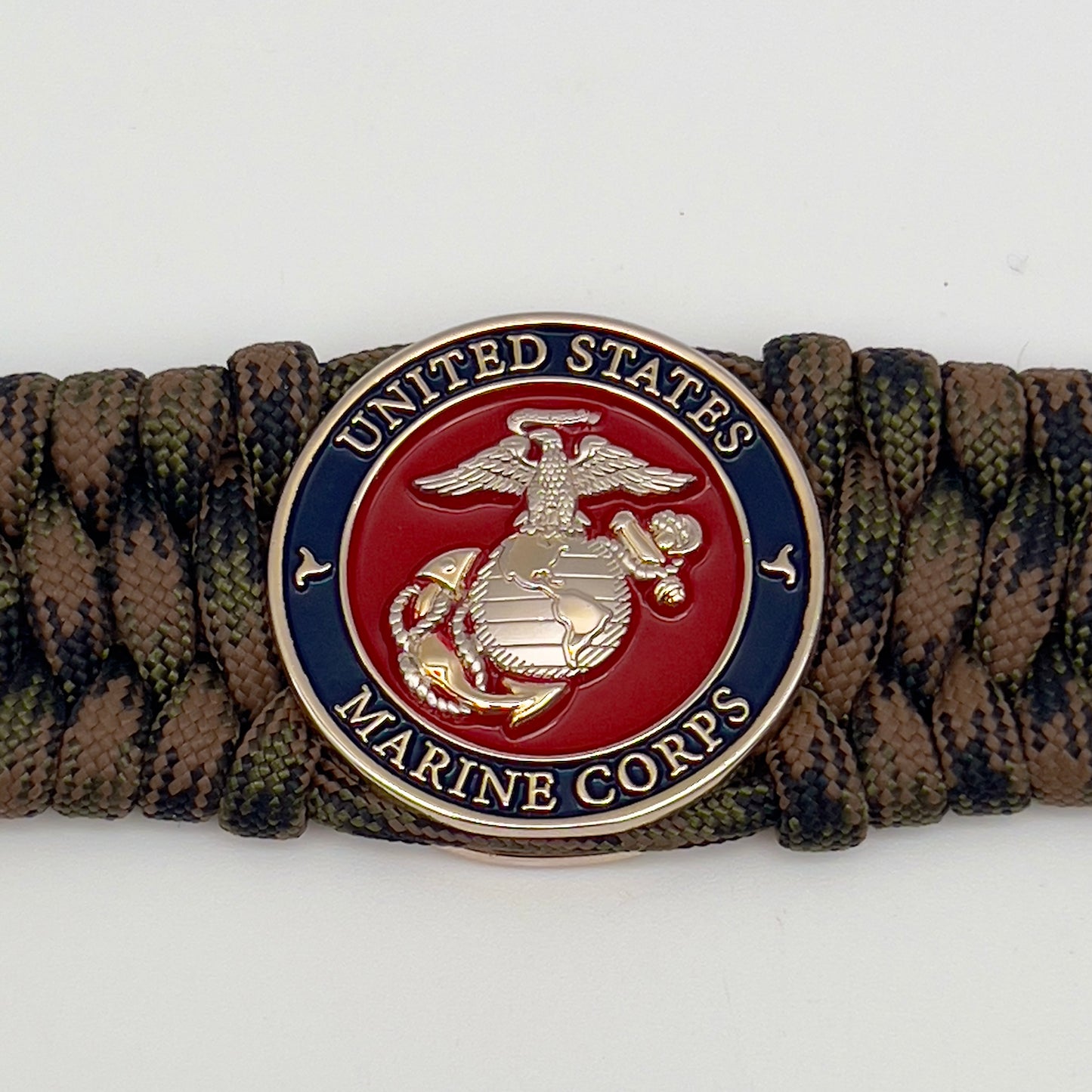 Thick, rigid and comfortable braided United States Marine Corps bracelet featuring a 24K gold and silver plated USMC officer Eagle Globe and Anchor medallion, a gold Cobra style tactical buckle and woven with Woodland Camo 550 paracord.