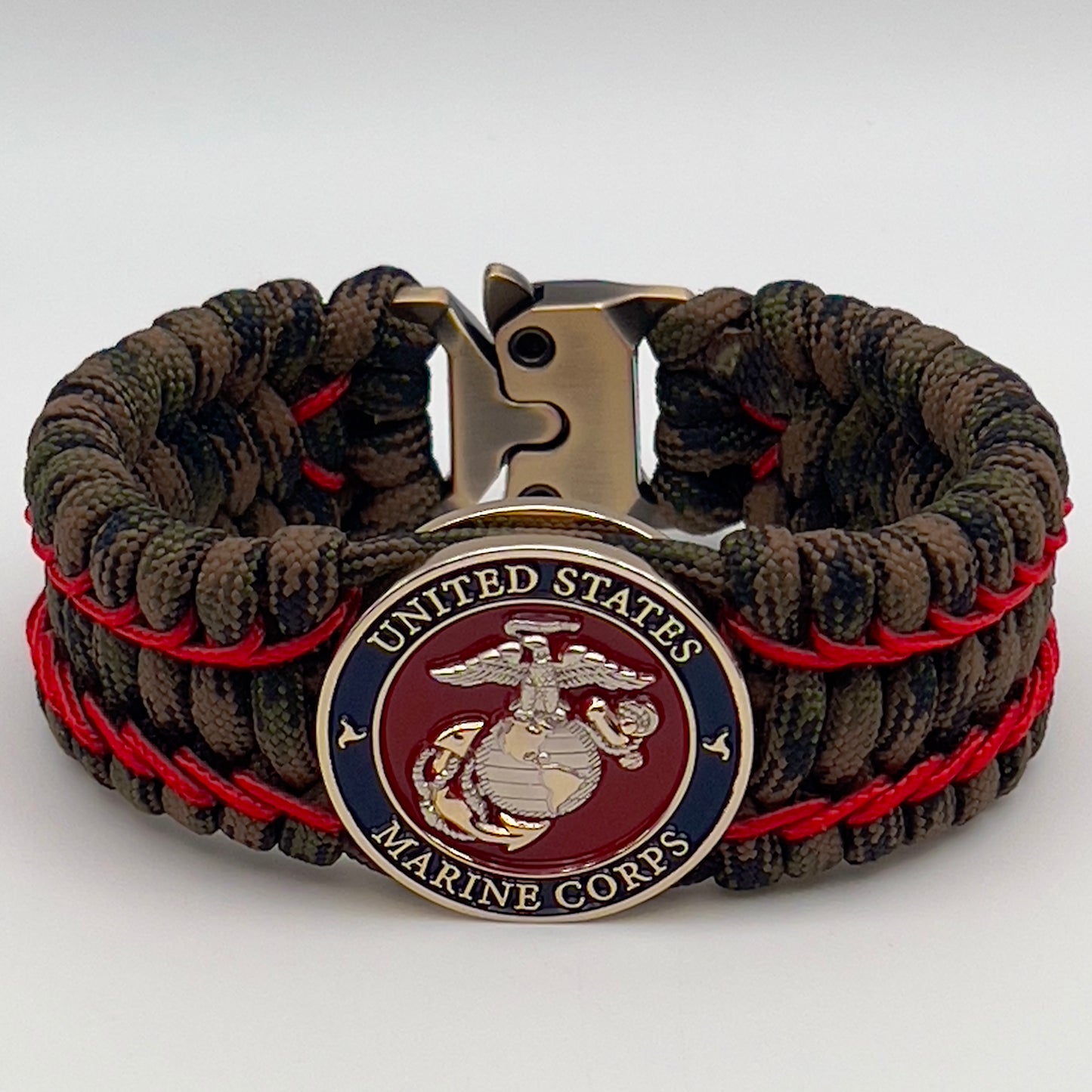 Thick, rigid and comfortable braided United States Marine Corps bracelet featuring a 24K gold and silver plated USMC officer Eagle Globe and Anchor medallion, a gold Cobra style tactical buckle and woven with Woodland Camo 550 paracord and Imperial Red micro cord.