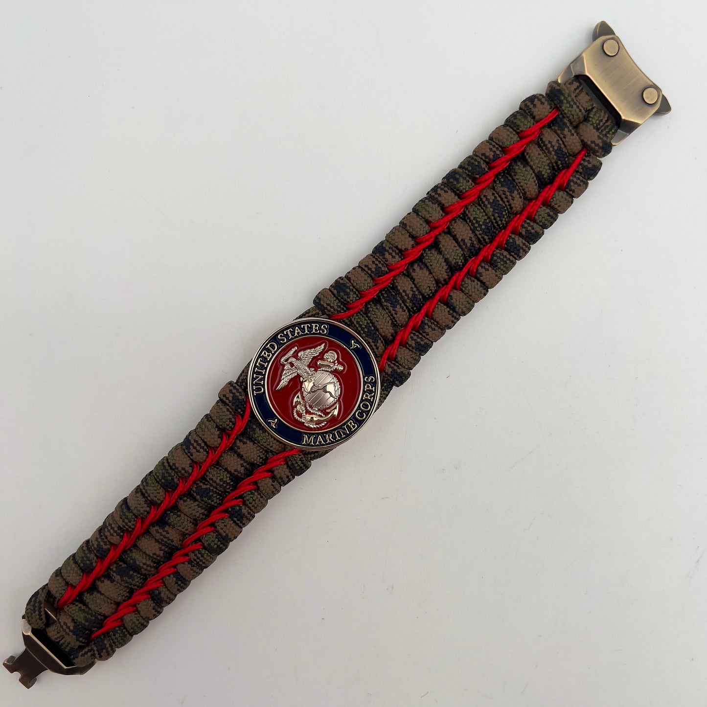 Thick, rigid and comfortable braided United States Marine Corps bracelet featuring a 24K gold and silver plated USMC officer Eagle Globe and Anchor medallion, a gold Cobra style tactical buckle and woven with Woodland Camo 550 paracord and Imperial Red micro cord.