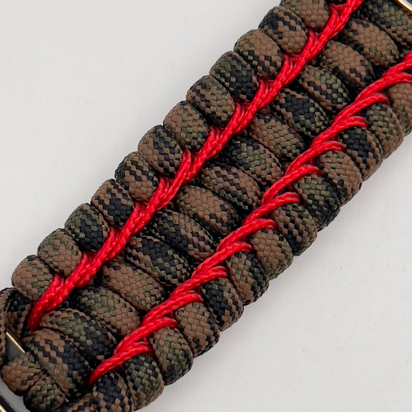Thick, rigid and comfortable braided United States Marine Corps bracelet featuring a 24K gold and silver plated USMC officer Eagle Globe and Anchor medallion, a gold Cobra style tactical buckle and woven with Woodland Camo 550 paracord and Imperial Red micro cord.