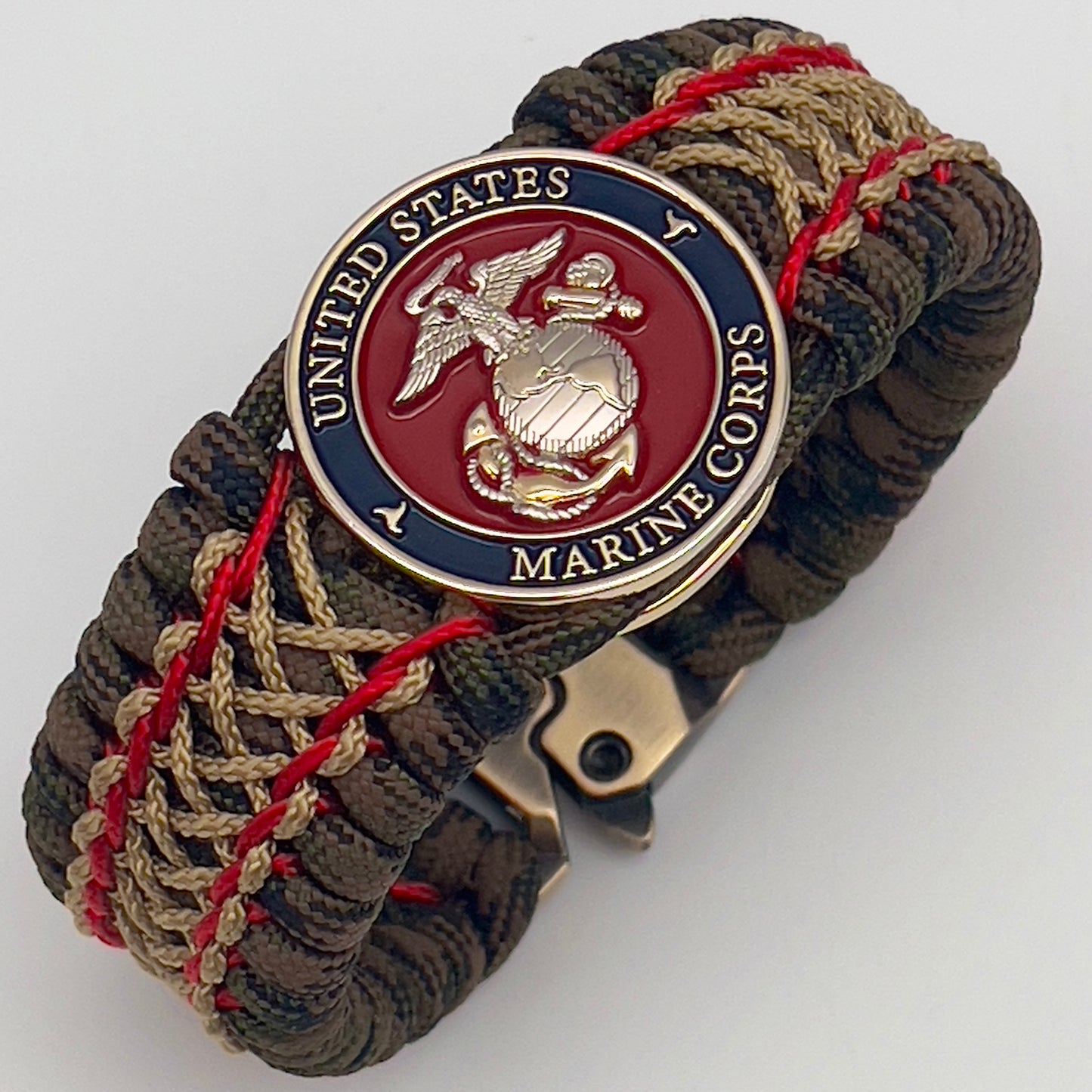 Thick, rigid and comfortable braided United States Marine Corps bracelet featuring a 24K gold and silver plated USMC officer Eagle Globe and Anchor medallion, a gold Cobra style tactical buckle and woven with Woodland Camo 550 paracord and Imperial Red and gold micro cord.