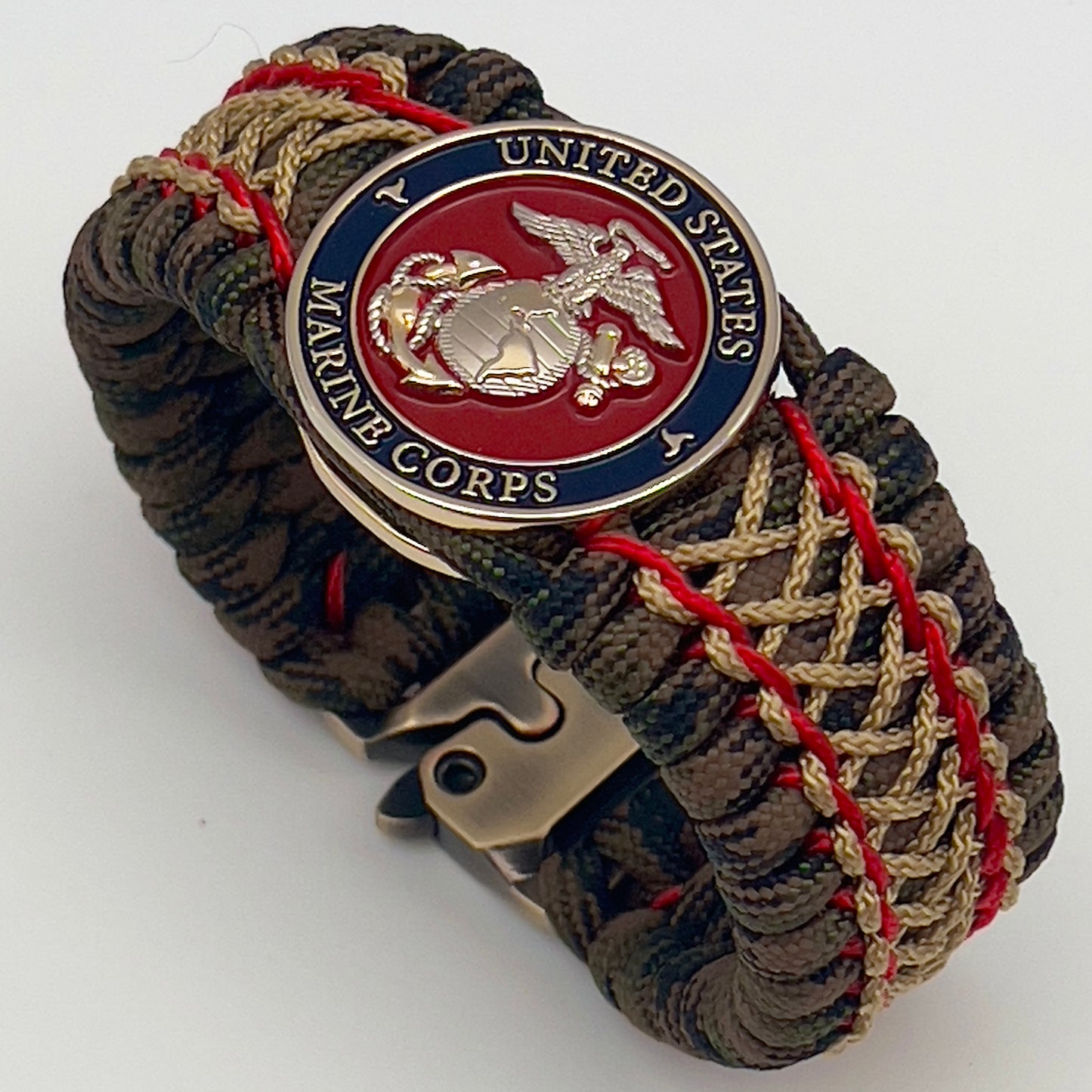 Thick, rigid and comfortable braided United States Marine Corps bracelet featuring a 24K gold and silver plated USMC officer Eagle Globe and Anchor medallion, a gold Cobra style tactical buckle and woven with Woodland Camo 550 paracord and Imperial Red and gold micro cord.