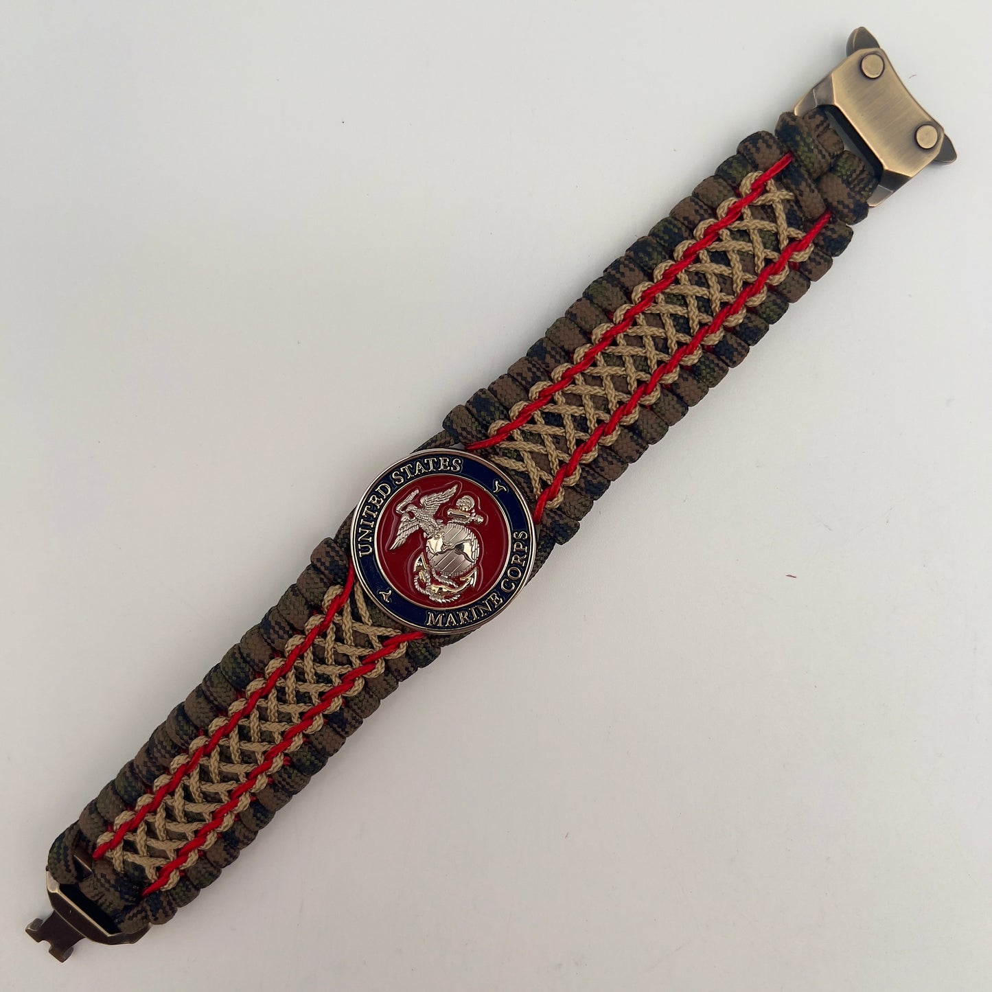 Thick, rigid and comfortable braided United States Marine Corps bracelet featuring a 24K gold and silver plated USMC officer Eagle Globe and Anchor medallion, a gold Cobra style tactical buckle and woven with Woodland Camo 550 paracord and Imperial Red and gold micro cord.