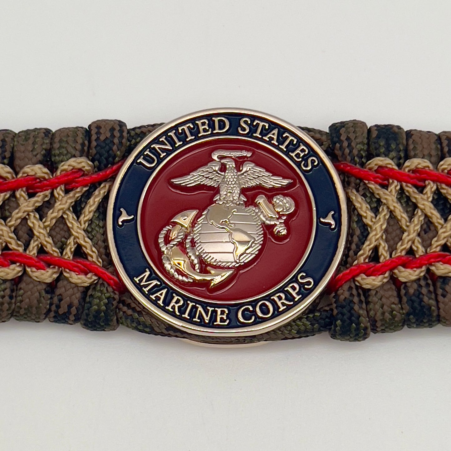 Thick, rigid and comfortable braided United States Marine Corps bracelet featuring a 24K gold and silver plated USMC officer Eagle Globe and Anchor medallion, a gold Cobra style tactical buckle and woven with Woodland Camo 550 paracord and Imperial Red and gold micro cord.