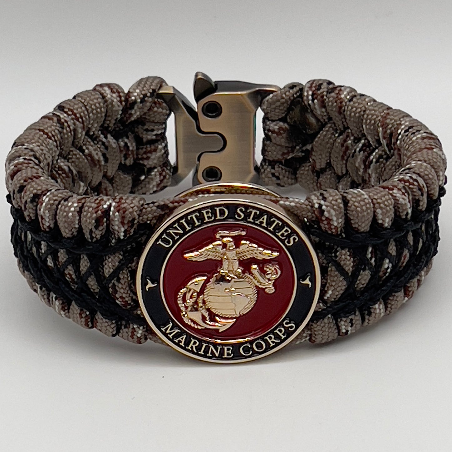 Thick, wide, rigid and comfortable braided United States Marine Corps bracelet featuring a 24K gold plated USMC Eagle Globe and Anchor medallion, a gold Cobra style tactical buckle and woven with Desert Camo 550 paracord and black nano and micro cord.